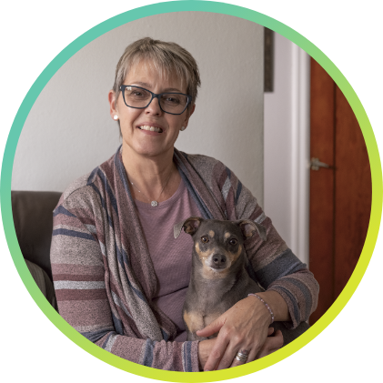 A woman sitting down with a dog in her lap.